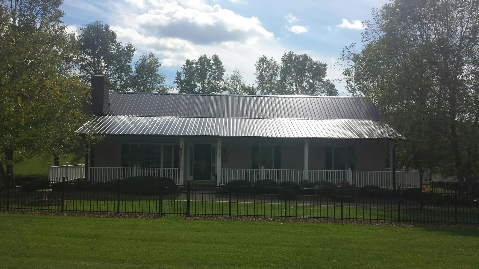 Gray metal roof on a brick ranch with a full width front porch — Gutter Guard Installation work by our crew in Stockton
